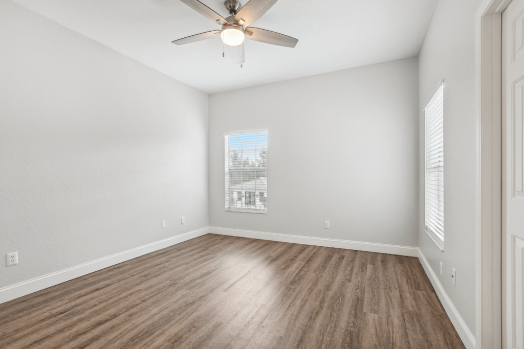 A room with a ceiling fan and wooden flooring.